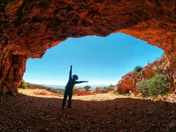 Man standing on rock against sky