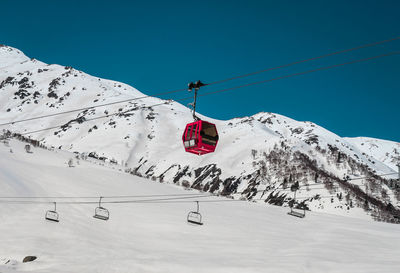 Overhead cable car on snowcapped mountains against sky