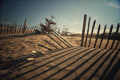 Shadow of wooden fence on field against sky