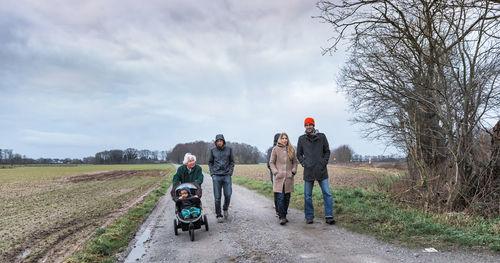 Family on road amidst field against sky