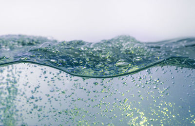 Close-up of water drops on glass against white background