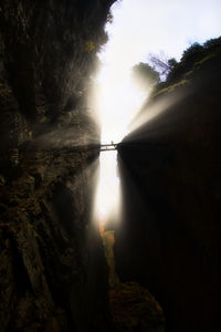 Sunlight streaming through rocks against sky