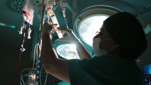 Side view of surgeon holding iv drip in operating room
