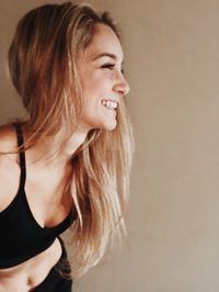 Portrait of smiling young woman against wall