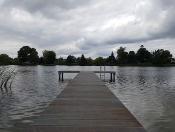 Pier on lake against cloudy sky