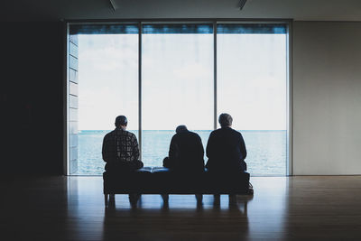 Rear view of people sitting in glass window