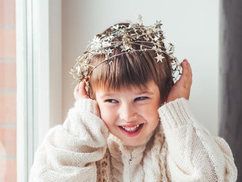 Kid with decorative star tinsel for christmas tree. boy in cable-knit oversized sweater. new year.