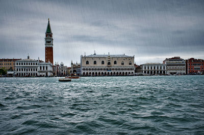 Buildings by sea against sky