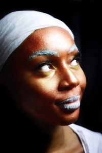 Close-up of woman with make-up looking away over black background