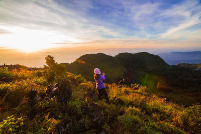 High angle view of woman standing on cliff against mountains