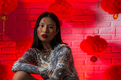 Portrait of woman standing against red wall