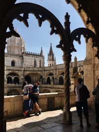 People walking outside historic building against sky