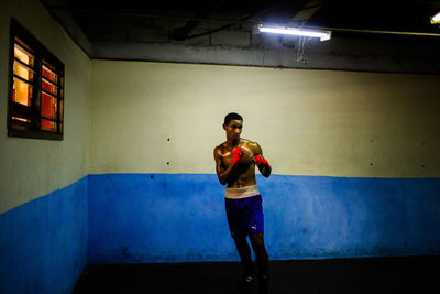 Full length of man standing against illuminated wall