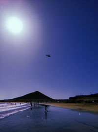 People at beach against clear sky