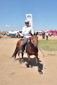 Man riding horses on land against sky