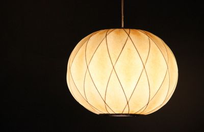 Low angle view of illuminated lighting equipment against black background