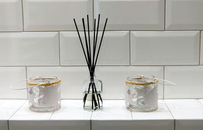 Incense holder and candle holders on white shelf in bathroom