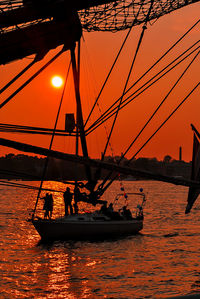 People standing on sailboat in river daugava during sunset against sky