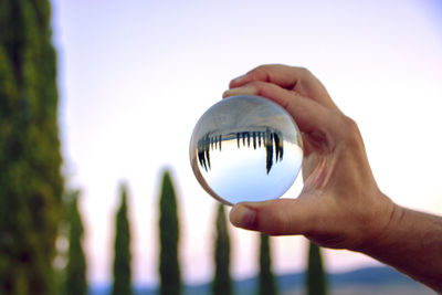 Reflection of person hand holding crystal ball in glass