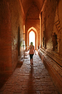 Rear view of woman walking in corridor of building