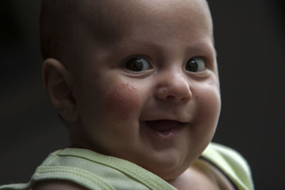 Portrait of smiling cute baby boy against black background