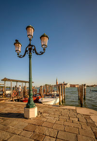 Street light on pier by grand canal against clear blue sky