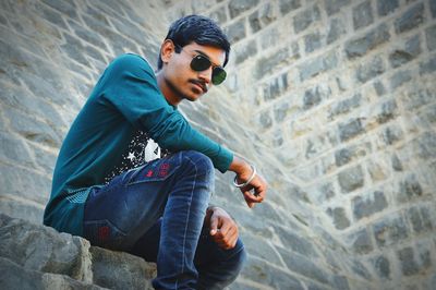 Young man wearing sunglasses against wall