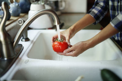 Close up of woman's hands washing a tomatoe