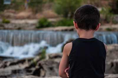 Rear view of boy looking at waterfall