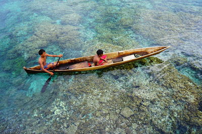 High angle view of men sitting on boat in sea