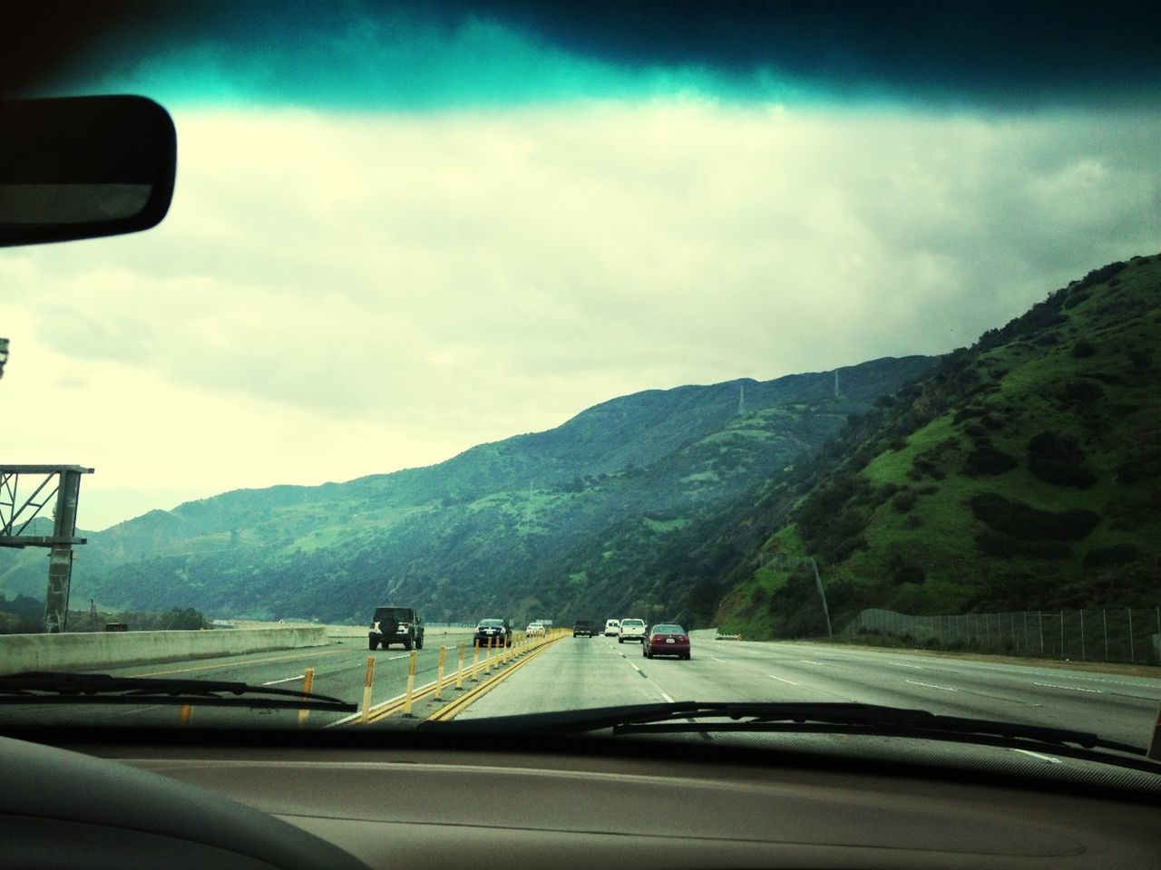 transportation, mode of transport, car, mountain, land vehicle, road, vehicle interior, sky, windshield, travel, mountain range, landscape, on the move, road marking, car interior, country road, journey, glass - material, cloud - sky, the way forward