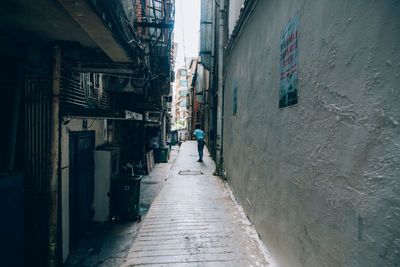 Man walking on alley amidst buildings