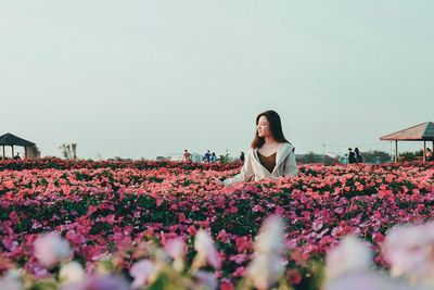 Woman with flowers in park against clear sky