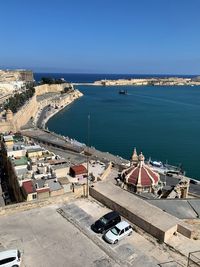 High angle view of buildings by sea against blue sky