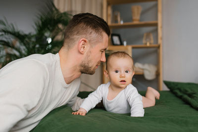 Close-up of a young caucasian father kissing a newborn. the little baby is happy and safe