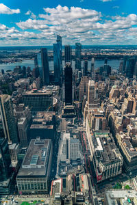 Aerial view of illuminated skyscraper buildings in city at day at high angle