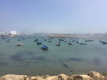 Boats moored on sea against clear sky