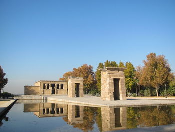 Temple of debod reflecting in lake against clear sky
