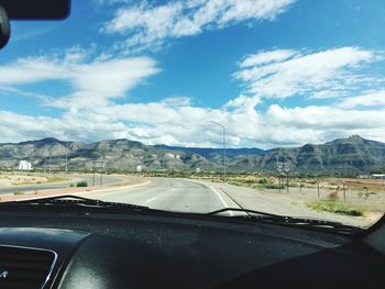 Cars on road against sky seen through car windshield