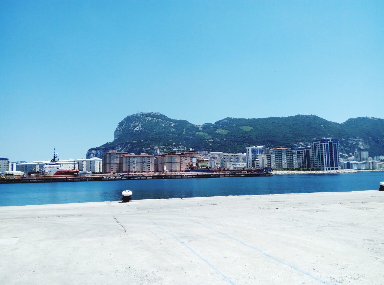 nautical vessel, clear sky, water, built structure, building exterior, transportation, architecture, mountain, copy space, sea, blue, mode of transport, harbor, ship, waterfront, day, cruise ship, outdoors, commercial dock, port, no people