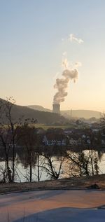 Smoke emitting from factory against sky