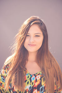 Portrait of woman with long brown hair against wall