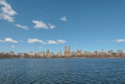 Scenic view of river by buildings against sky