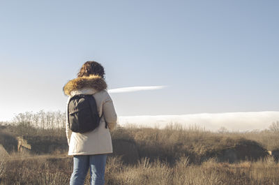 Rear view of woman standing on field against sky