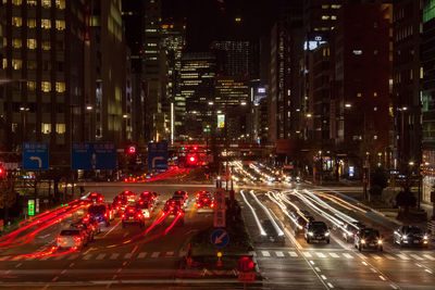 Vehicles with light trails on city street amidst buildings