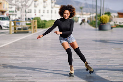 Portrait of woman roller skating on sidewalk in city