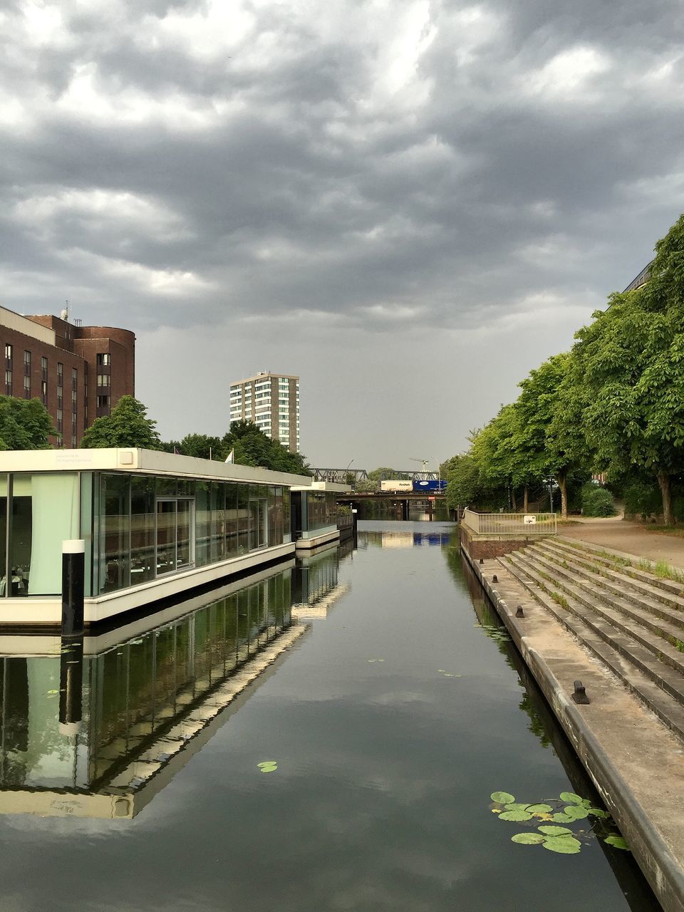 architecture, building exterior, built structure, sky, water, cloud - sky, cloudy, city, cloud, canal, residential building, reflection, residential structure, tree, waterfront, river, day, building, house, high angle view