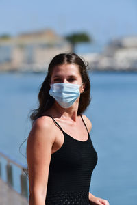 Portrait of young woman while standing against sky