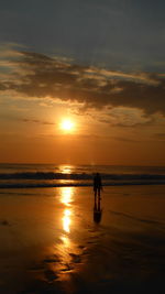 Silhouette woman walking at beach against sky during sunset