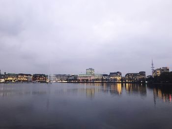 City at waterfront against cloudy sky